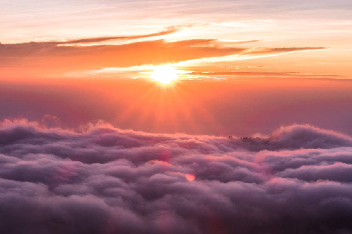 Image of an orange sunset above a bed of clouds. 