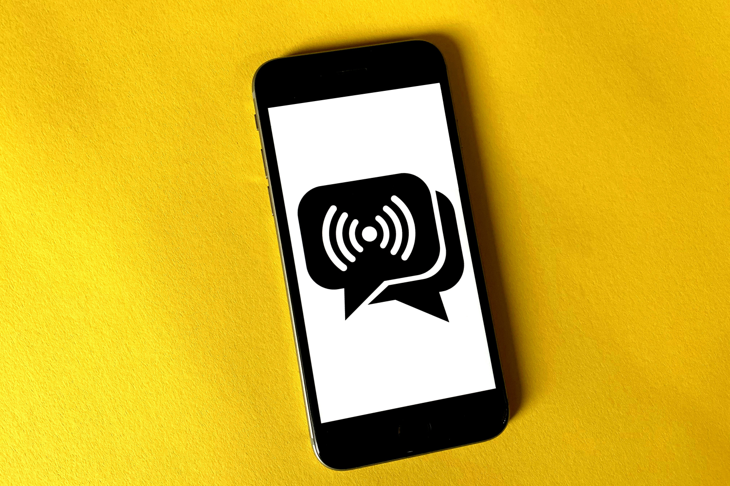Phone against a yellow background with a speech symbol on it.